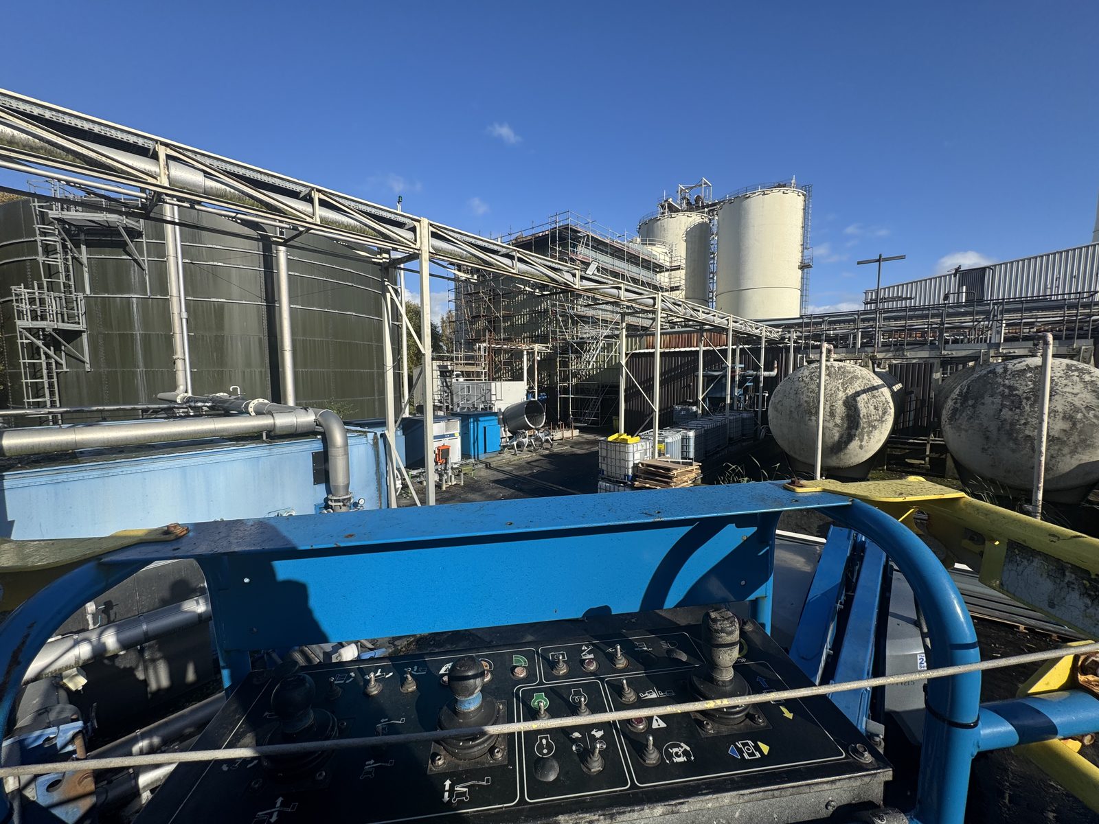Wide view of the Norit Activated Carbon facility from a cherry picker basket showing chemical storage tanks, silos, elevated pipe racks, and process equipment