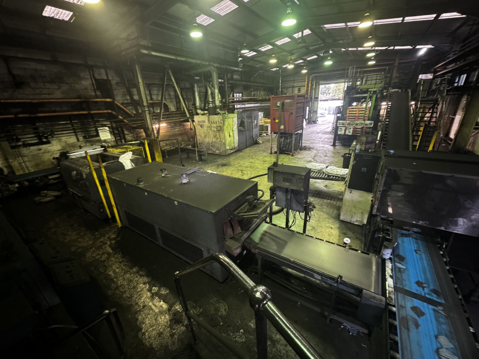 Norit Activated Carbon warehouse interior lit by old high-pressure sodium lights showing yellow-green light cast across production equipment and conveyors