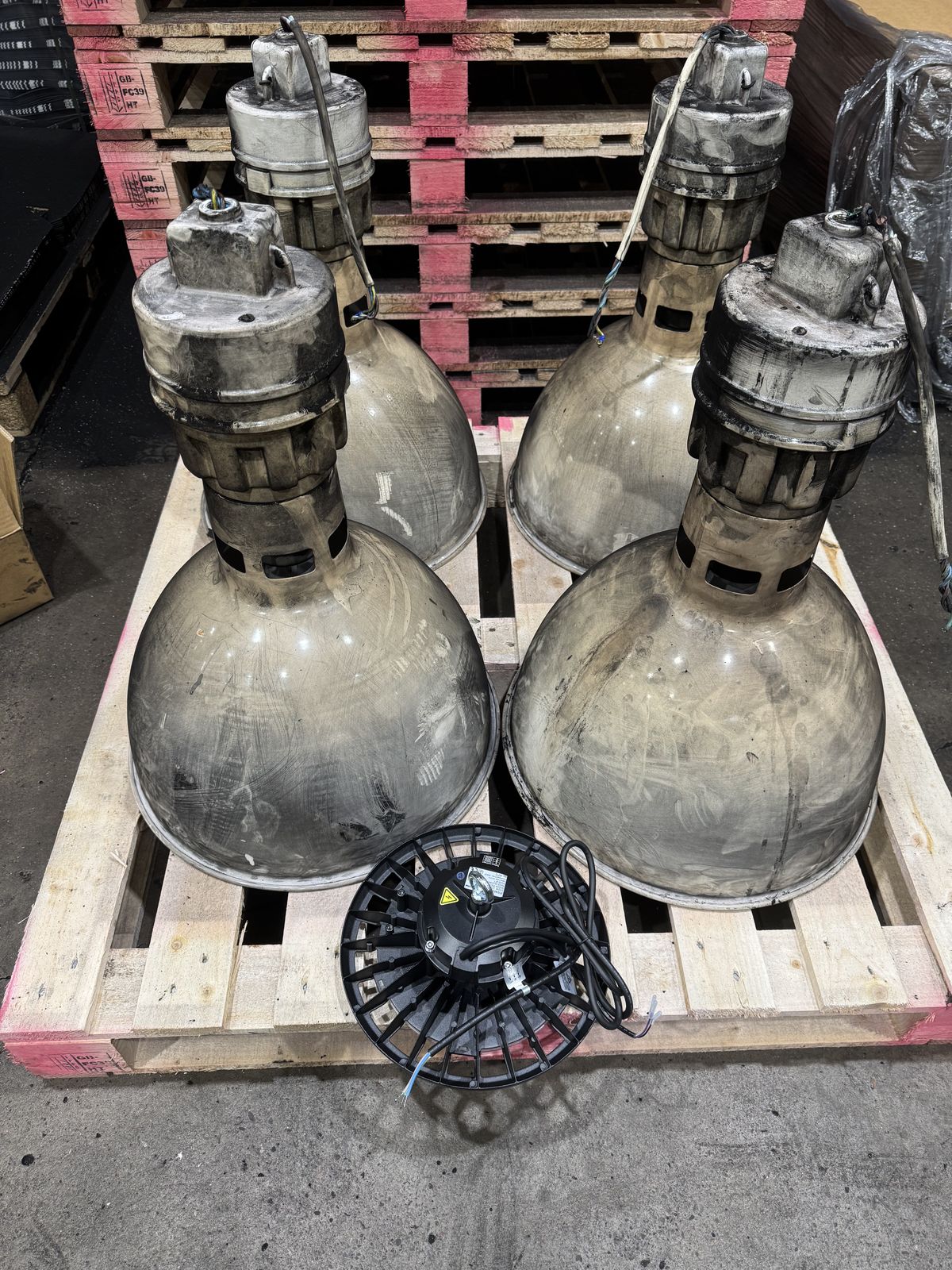 Four old 750W sodium high bay lights next to a compact 200W LED replacement showing the dramatic size and technology difference