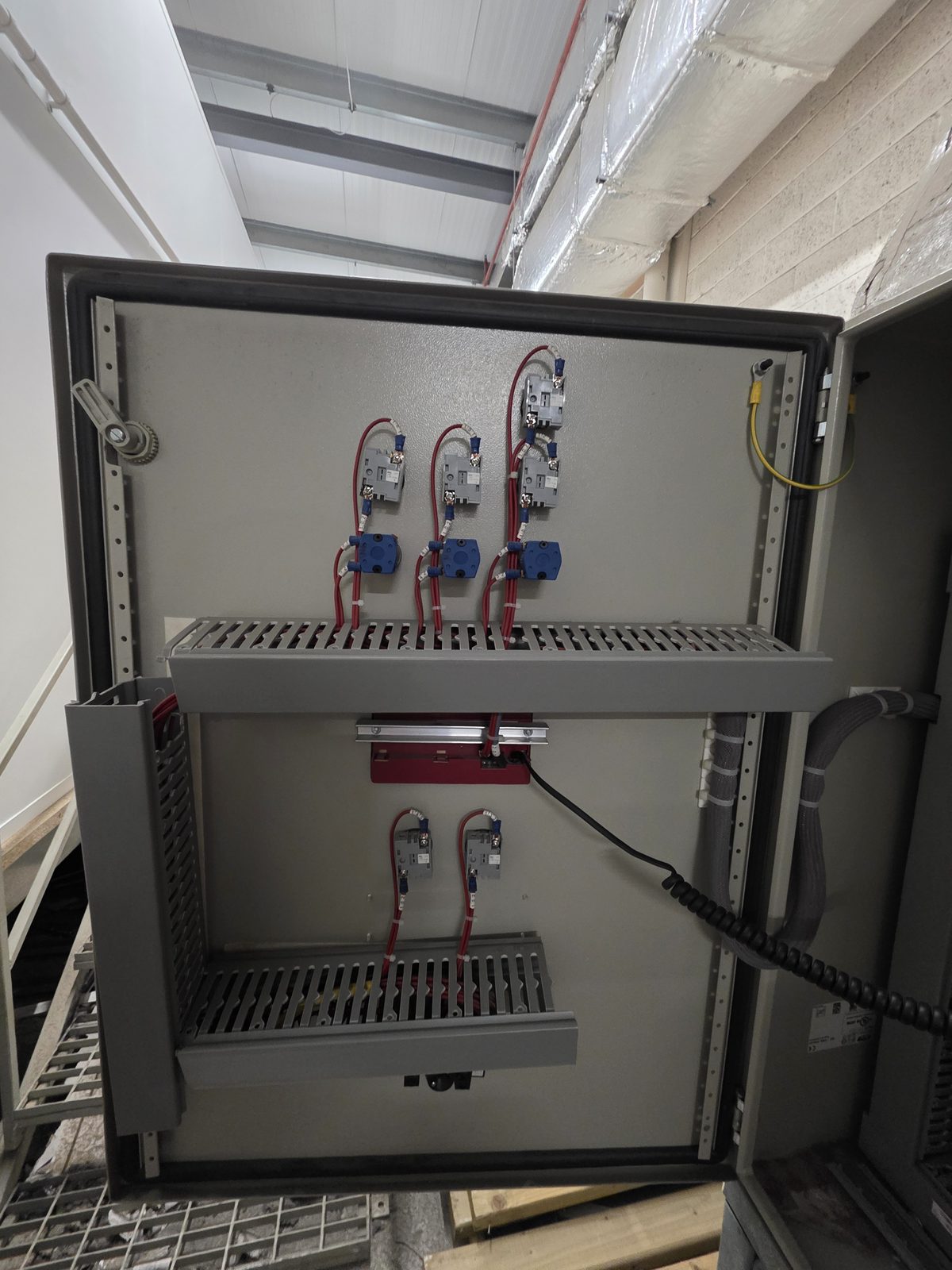 Contactor and MCB section of the AHU control panel showing contactors with blue pneumatic actuator valve overrides and red power wiring